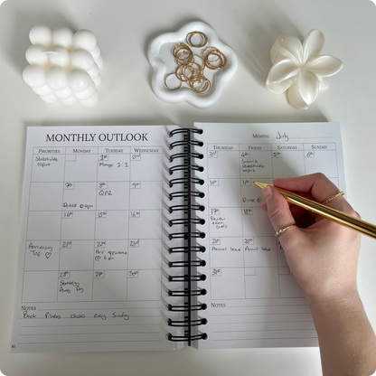 Monthly calendar layout in The Quarterly Navigator planner being filled in by hand — part of Agile Bloom's productivity system.